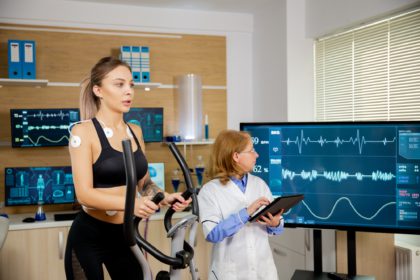 Fit female testing the stepper with electrodes on it and the doctor watching the evolution of the